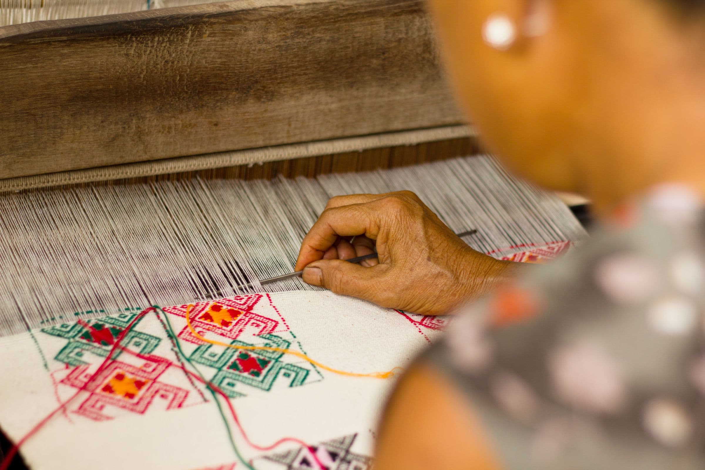 An artisan weaving fabric on a traditional loom